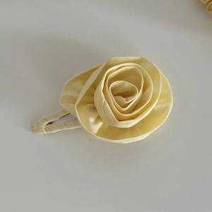 Detailed macro view of a soft yellow handmade satin rose flower hair clip accessory