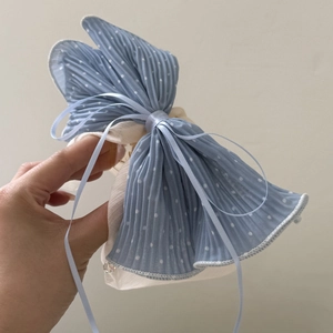 Close-up of blue polka dot pleated bow hair clip with decorative ribbon details
