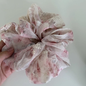 Detail of pink floral scrunchie with white lace embroidery and sheer mesh texture