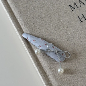 Barrette à fleurs avec nœud argenté et perles sur fond de livre texturé