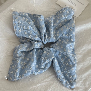 Detail of light blue embroidered flower scrunchie with white pearls on a soft background