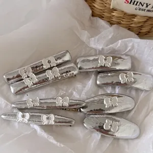 Set de 7 pinces à cheveux Y2K argentées avec nœuds et strass pour femmes sur blanc
