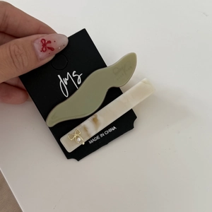 Dettaglio del set di fermagli per capelli in resina verde e motivo marmo beige