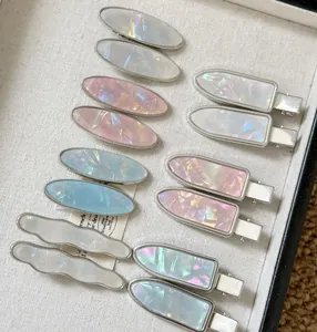 Détail de barrettes colorées en acétate et métal argenté avec texture nacrée et design ondulé