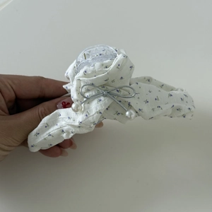 Détail d'une pince à cheveux à fleurs avec nœud argenté et pendentifs en perles
