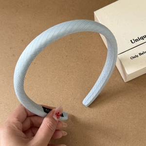 Detail of light blue checkered headband featuring twill texture and refined fabric wrapping