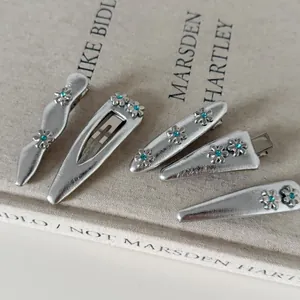 Dettaglio di cinque fermagli per capelli argento con trama in pelle e strass blu