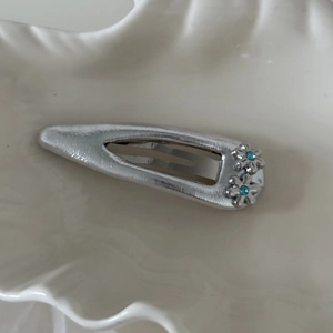 Dettaglio di un fermaglio per capelli a fiori argentati con strass blu su vassoio