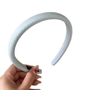 Handheld light blue striped headband with lace trim and elegant fabric texture details