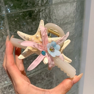 Détail de la pince à cheveux étoile de mer avec fleurs en soie roses et bleues et strass