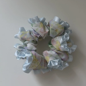 Detail of floral scrunchie with light blue satin ruffled edges and pink flower patterns