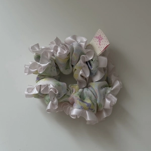 Detail view of floral ruffle hair scrunchie with pastel green fabric and silk satin edges