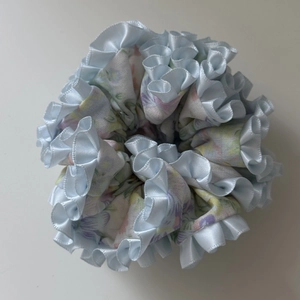 Detailed view of layered blue floral fabric hair scrunchie with light blue satin ruffled edges