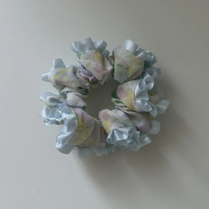 Detail of floral scrunchie with ruffled light blue satin edges and pink patterns
