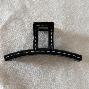 Minimalist black hair claw clip with white hand-drawn stitching on cotton fabric