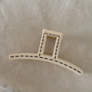 Macro view of cream hair claw clip with black dotted lines and golden metal spring