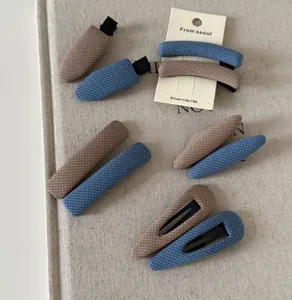 Detailed view of British style checkered fabric hair clips in navy blue and brown tones