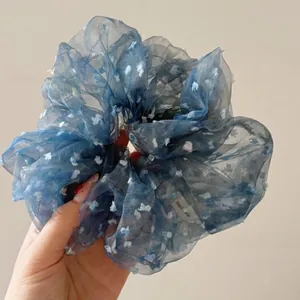 Detail eines blauen Organza-Haargummis mit Schmetterlingsstickerei und handgefertigtem Label