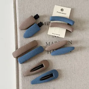 Detailed view of British style denim plaid fabric hair clips on a linen texture card