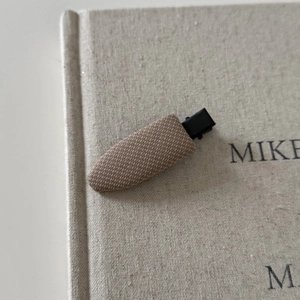 Vintage brown plaid fabric hair clip on a textured book cover for a classic aesthetic