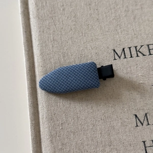 Macro shot of British style plaid fabric hair clip with a blue denim texture on beige background