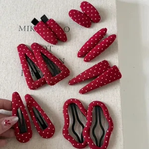 Close-up of red and white polka dot fabric hair clips in various geometric shapes