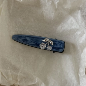 Détail de la pince à cheveux marbrée bleue avec motif cerise argenté en strass