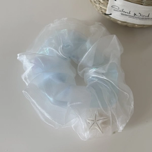 Detail eines hellblauen Organza-Haargummis mit weißem Seestern-Anhänger und Faltenstoff