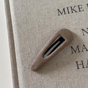 Macro shot of khaki plaid fabric hair clip on book cover, showcasing minimalist British style