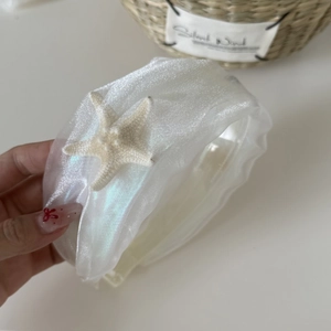 Detail eines weißen Haarreifs aus Mesh mit Faltenstoff und dekorativem beigem Seestern