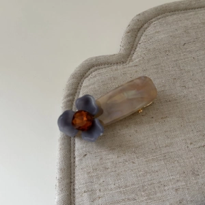 Détail de la pince à cheveux vintage avec fleur bleue mate et ornement en ambre