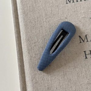 Macro detail of dark blue denim fabric hair clip with a refined twill texture
