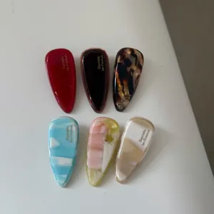 Detailed flat lay of six colorful acetate water drop hair clips with marble patterns