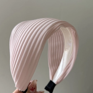Close-up of pink pleated wide headband showing fine vertical stripes and soft fabric texture
