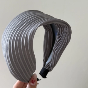 Detail of grey pleated headband showing fine vertical striped texture and soft fabric