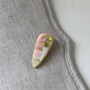 Close-up of pink acetate teardrop hair clip with marble texture on linen fabric