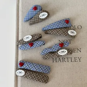 Detail of blue and brown plaid fabric hair clips with red hearts on linen background