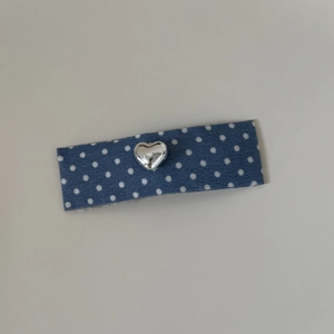 Détail d'une pince à cheveux à pois bleus avec un ornement en métal en forme de cœur