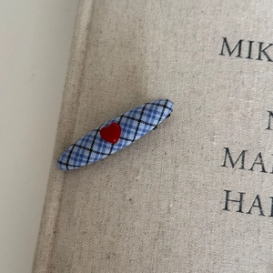 Close-up of blue checkered hair clip featuring a red 3D heart on a textured background