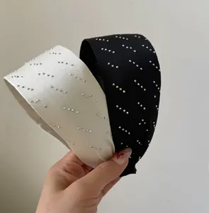 Détail de larges serre-têtes scintillants noirs et crème avec strass argentés fins