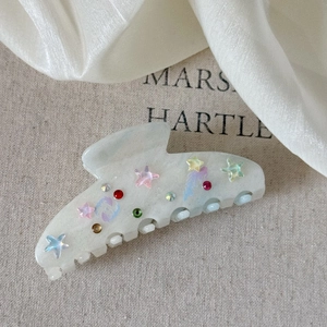 Macro shot of acetic acid hair claw clip with colorful stars and sparkling rhinestones
