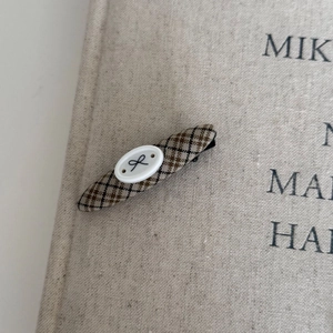 Detailed view of vintage plaid fabric hair clip on aesthetic book background