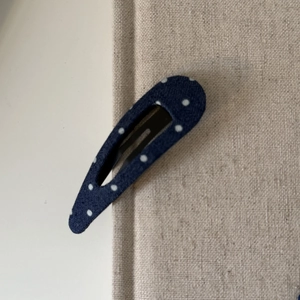 Détail d'une pince à cheveux goutte en denim bleu à pois blancs avec support métallique