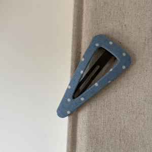 Gros plan d'une pince à cheveux en denim bleu à pois montrant la texture et le ressort