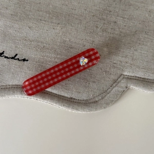 Detail einer rot-weißen Gingham-Haarklammer mit schillerndem herzförmigem Strass