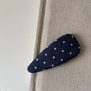 Gros plan sur une pince à cheveux en denim à pois bleus sur un fond en toile beige