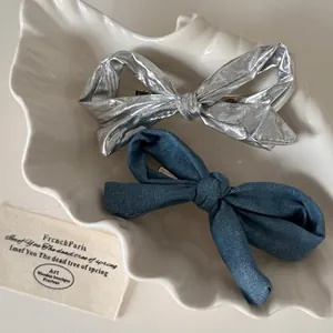 Elegantes Set aus Denim und silbernen Schleifen-Haarspangen auf einer weißen Schale