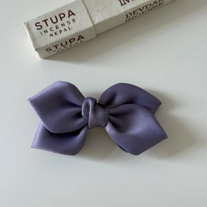 Detail view of a premium purple satin bow hair clip with layered silk ribbon texture