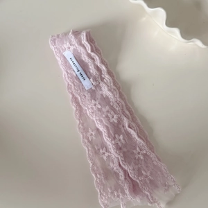 Pink star lace scarf hair ribbon with floral embroidery and brand label on white surface