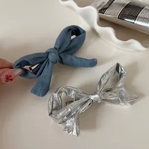 Silber-Metallic und blaue Denim Schleifen-Haarspangen auf einem Wellen-Porzellan-Teller